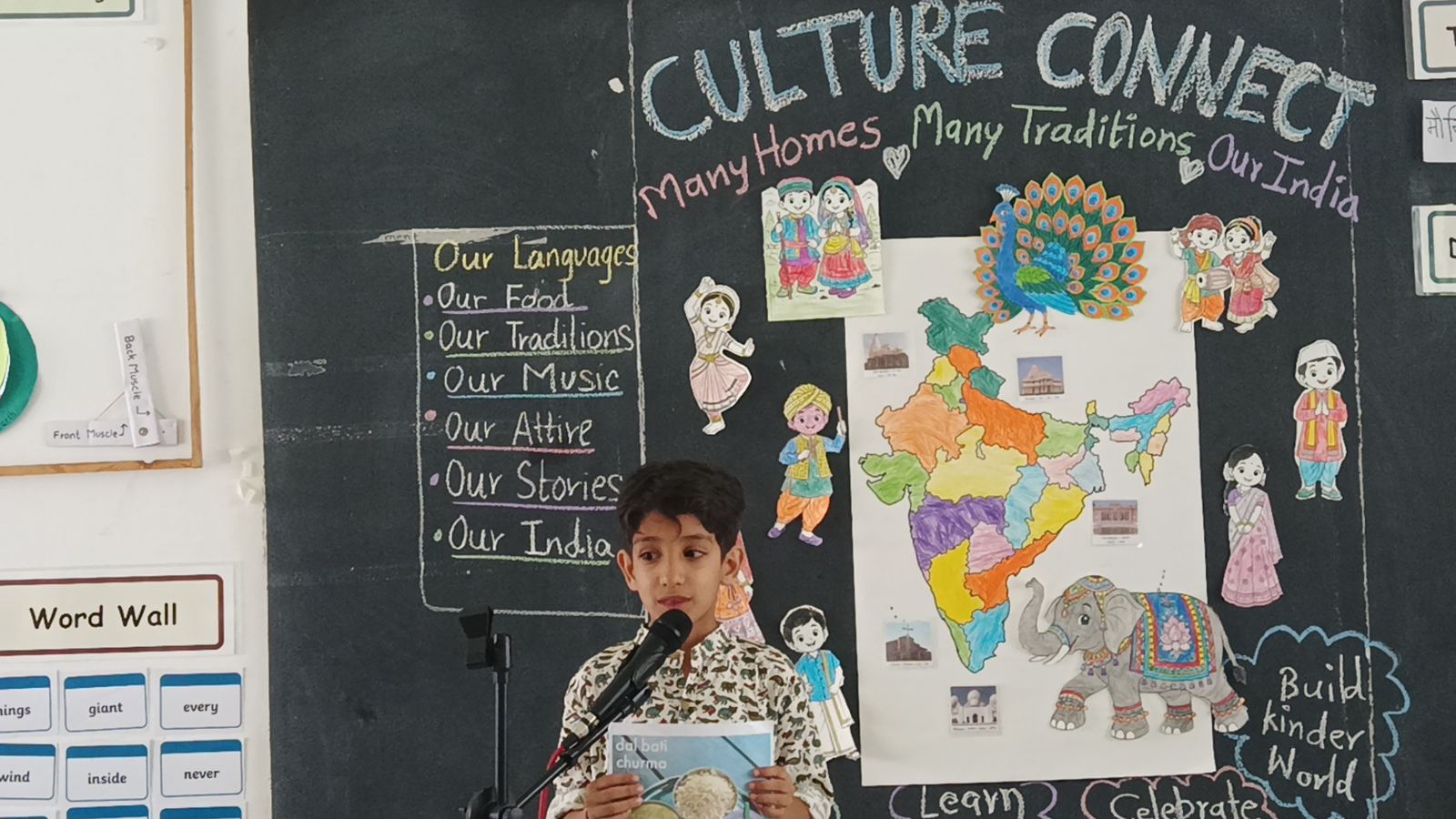 A girl in a pink kurta speaks into a microphone in front of the Culture Connect board