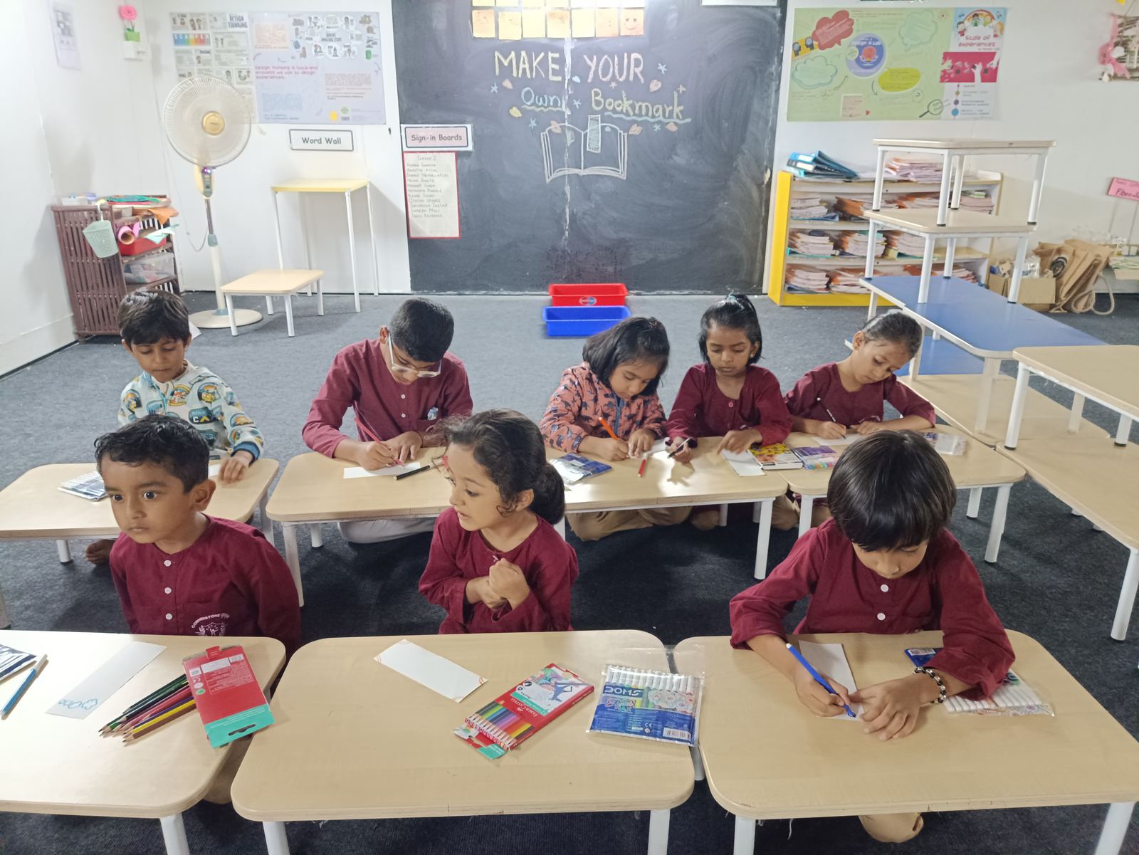 A Grade 2 class at work with coloured pencils at low desks