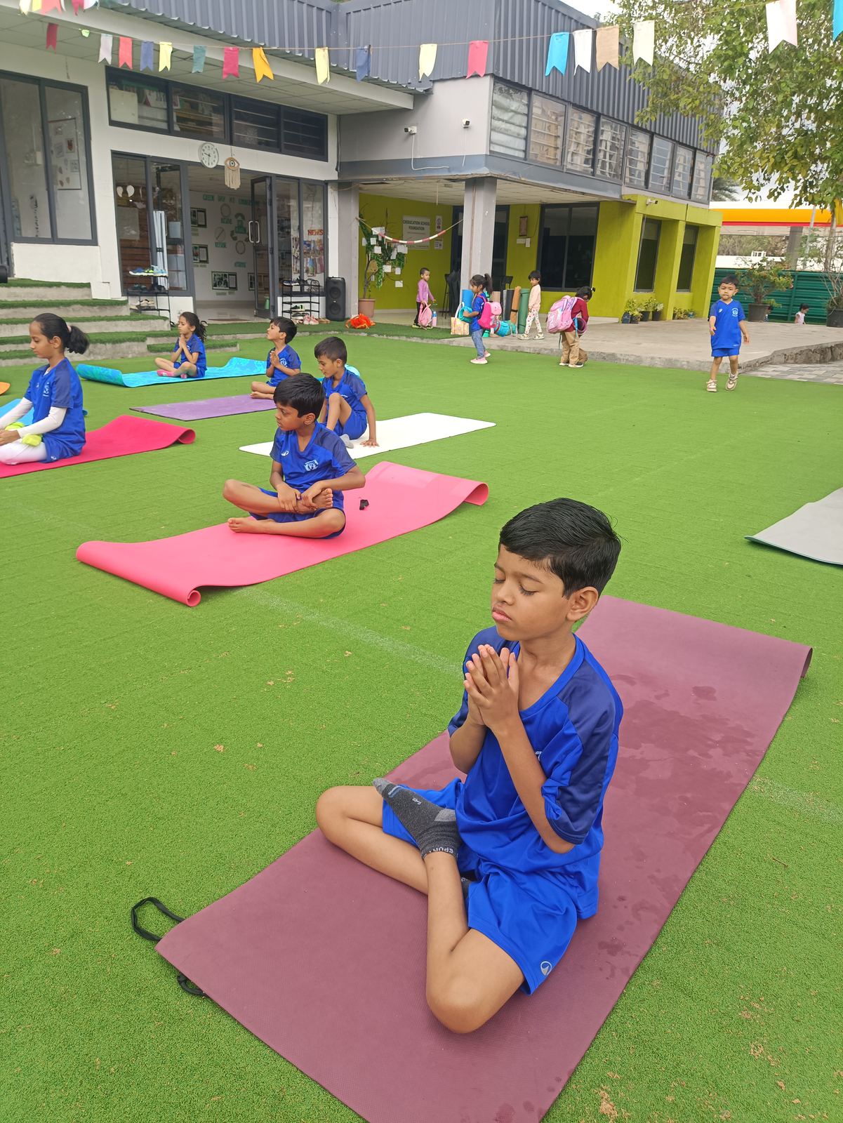 A child sits on a yoga mat on the green turf